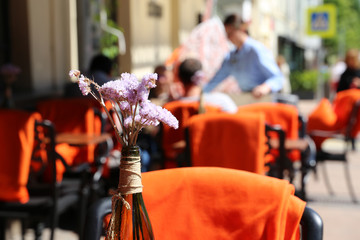 People in street cafe, tables in a restaurant outdoor. Romantic dinner in summer city, visitors and waiter, elegant setting for celebration and date