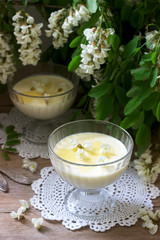 Panna cotta with robinia flavor, served with honey and white Robinia flowers. Rustic style.