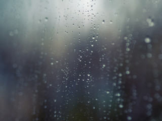 ..Raindrops on the surface of window glass with a blurred background.