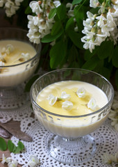 Panna cotta with robinia flavor, served with honey and white Robinia flowers. Rustic style.