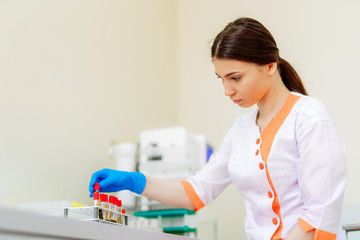 Beautiful laboratory technician woman in medical uniform works with blood samples. Female...