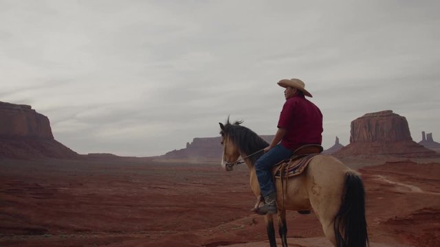 Model released Navajo man on horseback in front of red rock formations in Monument Valley, Arizona, USA. 4K UHD 60 FPS SLOW MOTION