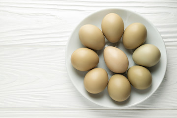 Top view pheasant eggs in a plate on a white wooden table