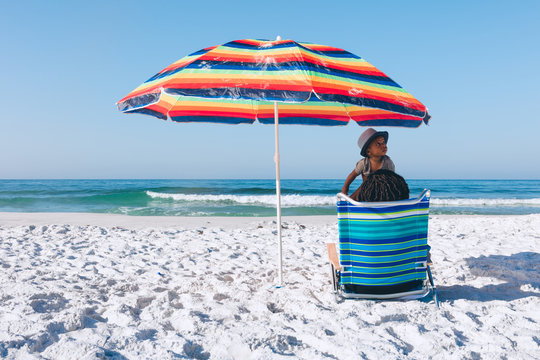 Black mother and son sitting on beach