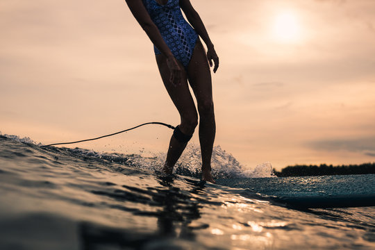 Young woman surfing waves in the ocean at sunset