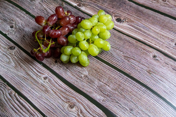 Red and yellow seedless grape on top of wooden table ready to be served.