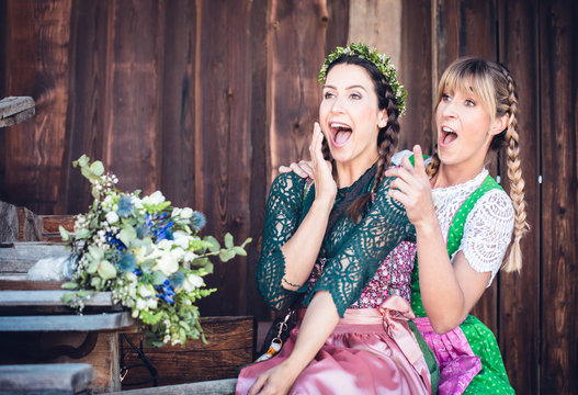 Junge Frauen im Dirndl Tradition Oktoberfest vor Holzhintergrund 