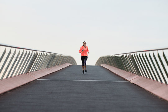 Jogger Running On Bridge Against Sky