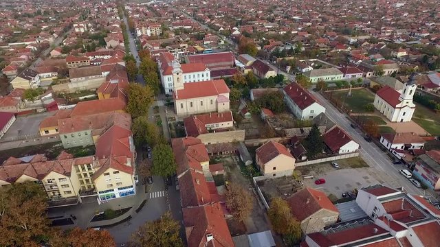 Low angle aerial fly over to red cherry color buildings and The church of Holy Martyr George, Novi Becej 