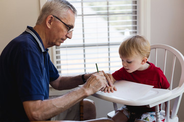 grandfather tracing his toddler grandson's hand
