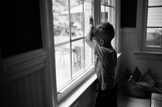 Moody black and white images of a bored young boy looking out a window