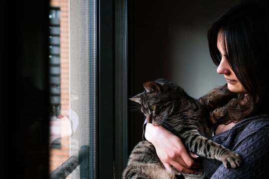 Lovely woman taking care of her cat at home.