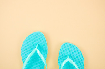 Flat lay frame blue beach slippers isolated on a pastel beige background. Top view with copy space