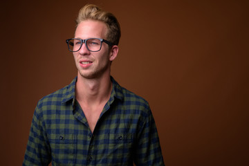 Obraz premium Studio shot of young handsome man against brown background
