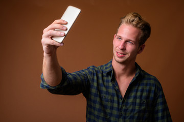 Studio shot of young handsome man against brown background