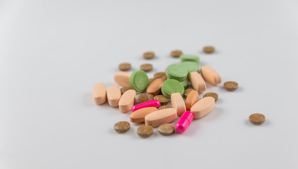 orange pink green round long pills and vitamin capsules for health on a white background