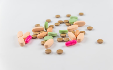 orange pink green round long pills and vitamin capsules for health on a white background
