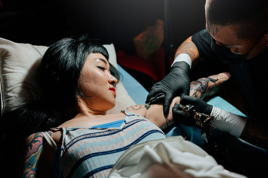 Professional asian tattooer makes a tattoo