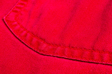 clothing items stonewashed red cotton fabric texture with seams, clasps, buttons and rivets, macro