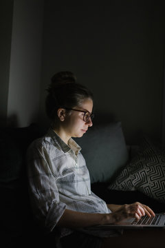 young woman with laptop on the sofa at night