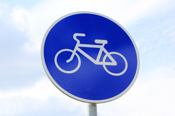 Bike route sign isolated on cloudy sky background. Simple blue and white bike lane indication for cyclists 
