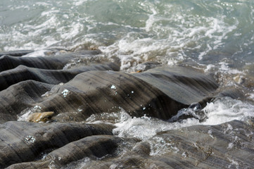pebble stones on the sea beach, the rolling waves of the sea with foam
