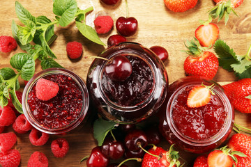 assortment of jams, seasonal berries, cherry, mint and fruits in glass jar