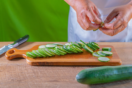 Guy cutting a zukini in slices. A knife and green zukini