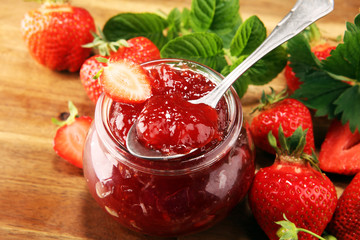 strawberry jam with fresh strawberries and mint. marmalade on spoon and jar on brown wood