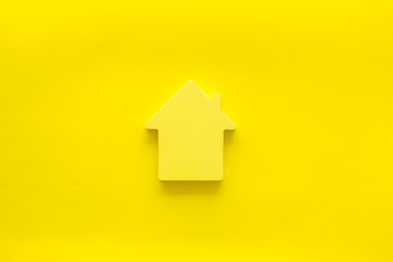 Property insurance concept with house toy on yellow background top view