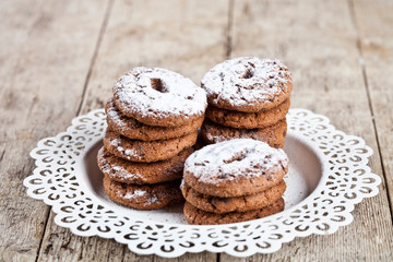 Fresh baked chocolate chip cookies with sugar powder heap on white plateon rustic wooden table