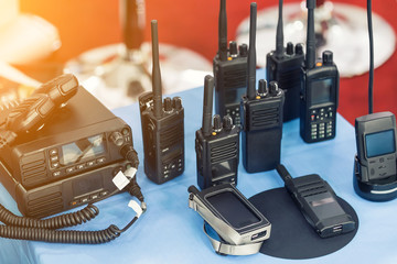 Many portable radio transceivers on table at technology exhibition. Different walkie-talkie radio...