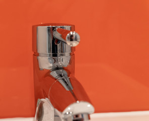 silver tap washbasin and orange background