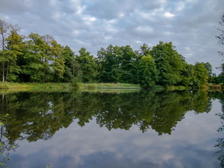 Fototapeta na wymiar Cloudy spring day beautiful nature reflection on the lake surface