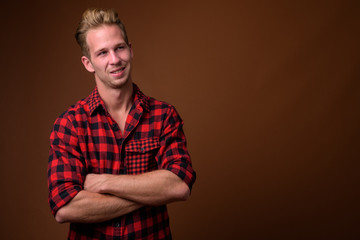 Studio shot of young handsome man against brown background