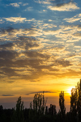 Landscape with dramatic light - beautiful golden sunset with saturated sky and clouds.