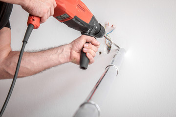 Handwerker bohrt Loch in die Wand mit einer Schlagbohrmaschine in einer Wohnung