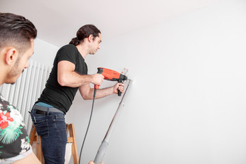 Handwerker bohrt Loch in die Wand mit einer Schlagbohrmaschine in einer Wohnung