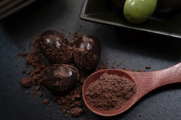 Chocolate round with cocoa powder wooden spoon and plate on top of Black rock stone plate