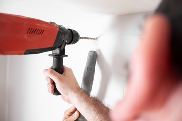 Handwerker bohrt Loch in die Wand mit einer Schlagbohrmaschine in einer Wohnung