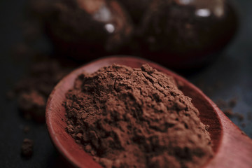 Chocolate round with cocoa powder wooden spoon and plate on top of Black rock stone plate