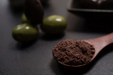 Chocolate round with cocoa powder wooden spoon and plate on top of Black rock stone plate