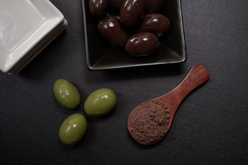 Chocolate round with cocoa powder wooden spoon and plate on top of Black rock stone plate
