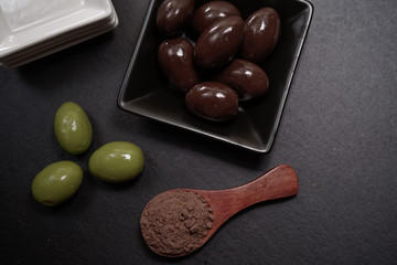 Chocolate round with cocoa powder wooden spoon and plate on top of Black rock stone plate