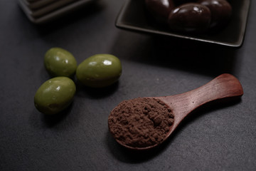 Chocolate round with cocoa powder wooden spoon and plate on top of Black rock stone plate