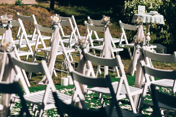 wedding ceremony in nature. Rows of white chairs on the lawn.