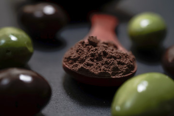 Chocolate round with cocoa powder wooden spoon and plate on top of Black rock stone plate