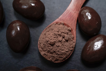 Chocolate round with cocoa powder wooden spoon and plate on top of Black rock stone plate