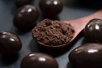 Chocolate round with cocoa powder wooden spoon and plate on top of Black rock stone plate
