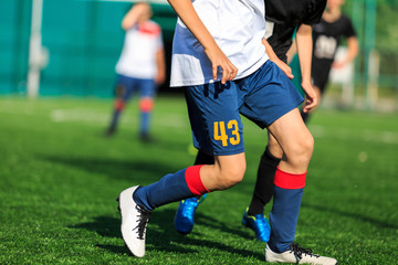 Boys at blue white sportswear run, dribble, attack on football field. Young soccer players with ball on green grass. Training, football, active lifestyle for kids	
